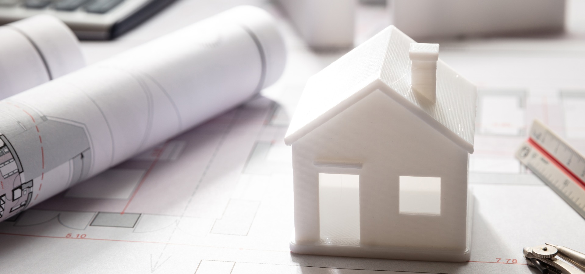 Dokumente und Miniaturhaus als Symbol für die Immobilienbewertung in Rostock